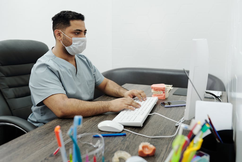 A Man wearing a Face Mask Using Computer