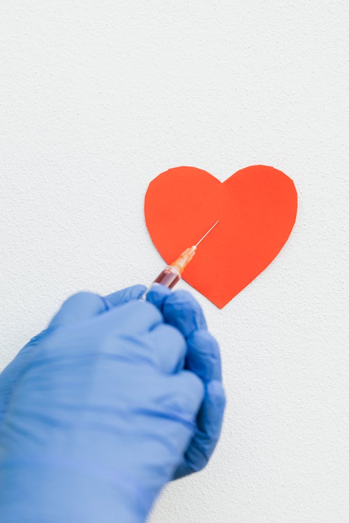 A gloved hand holds a syringe near a heart shape, symbolizing medical care.