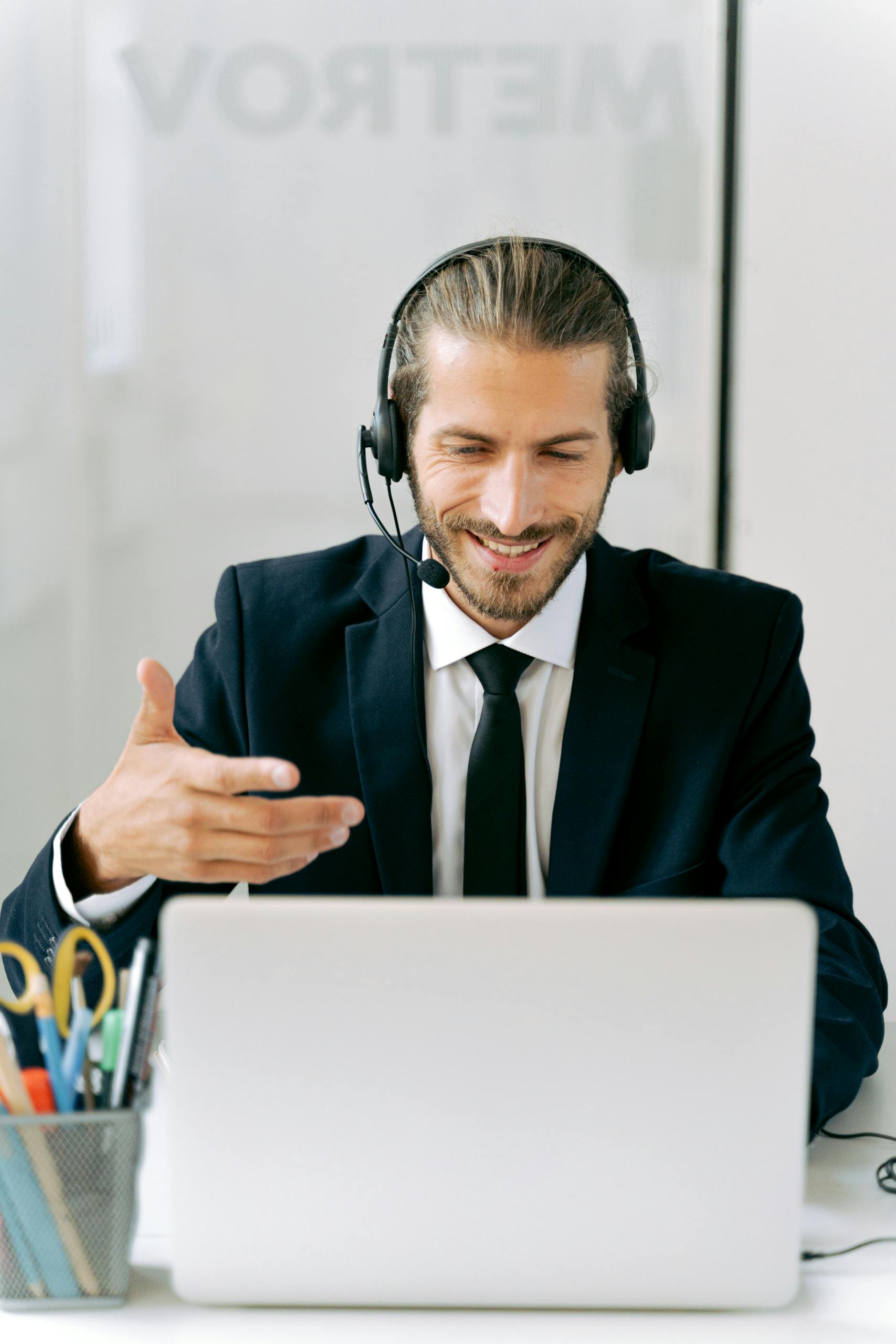 Confident businessman in suit with headset conducting an online meeting from office.